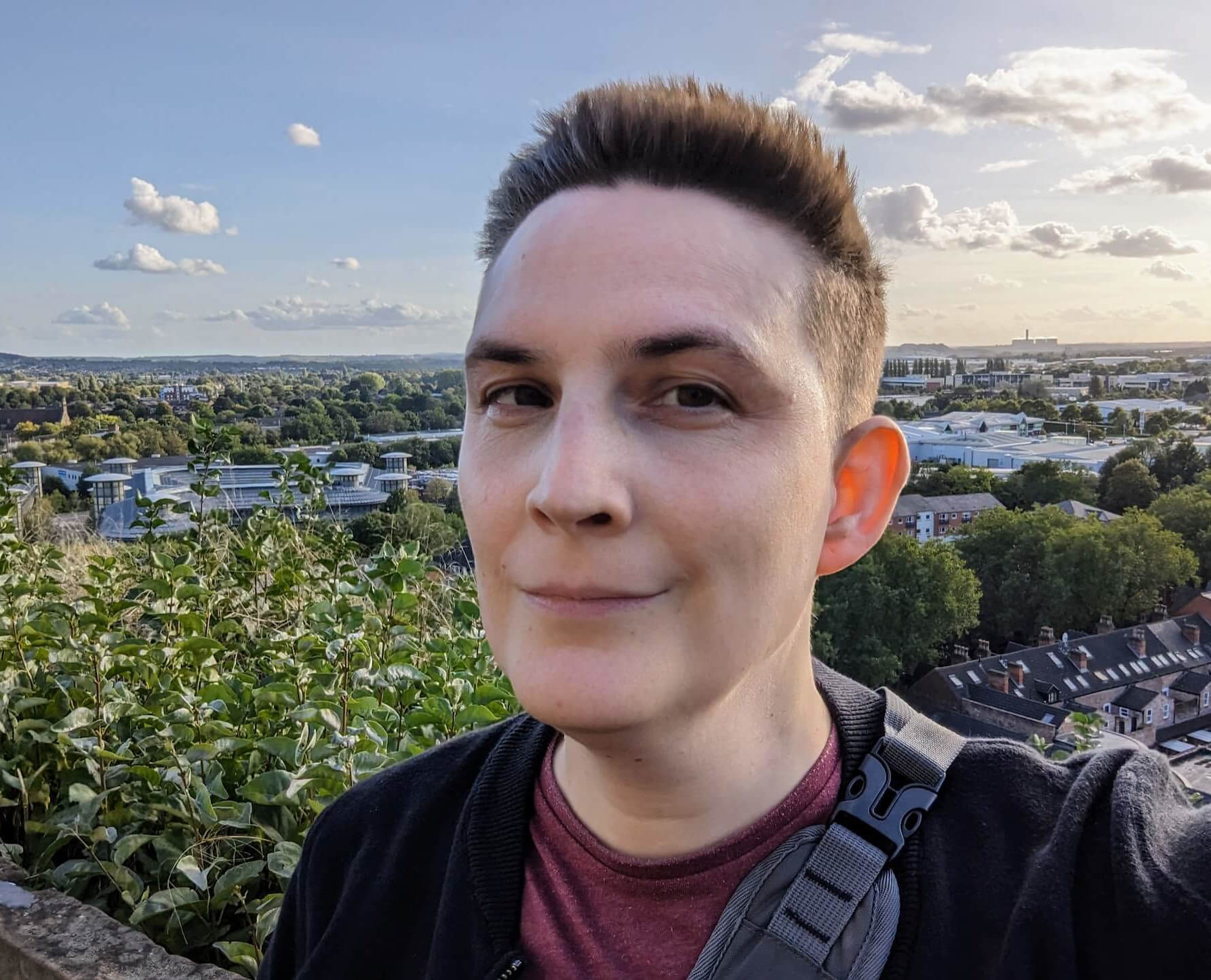 Nat Titman; a middle aged white person with short dark brown hair, stood in front of the view of Nottingham from the Castle, surrounded by greenery.